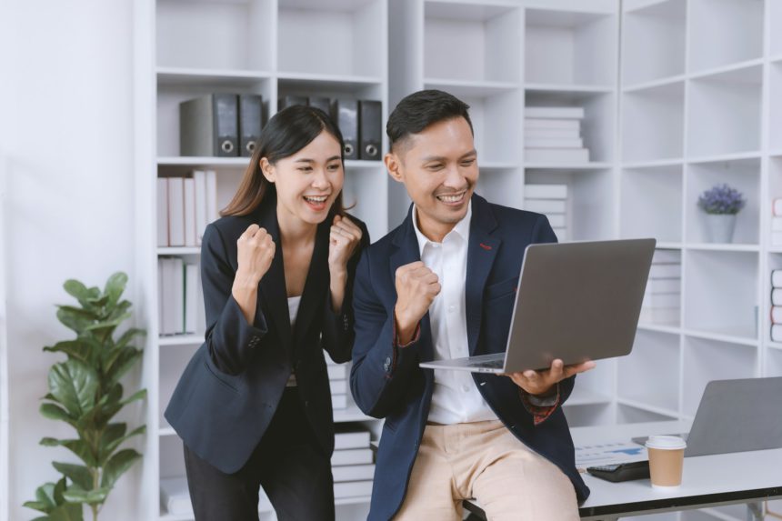 business people raising their hand to congratulate their achievement and rejoice with their laptop