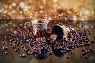 Coffee cup full of roasted coffee beans.