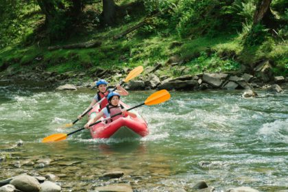 Happy people having adventure on mountain river. Rafting in small boats