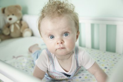 Portrait of baby girl lying in cot