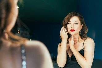 Portrait of posh woman with makeup and stylish dark hair in elegant cocktail silk black dress