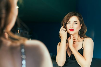 Portrait of posh woman with makeup and stylish dark hair in elegant cocktail silk black dress