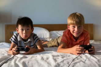 Siblings playing video game on bed