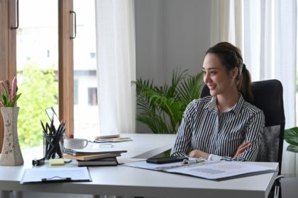 Thoughtful businesswoman team leader sitting at workplace and looking through window.