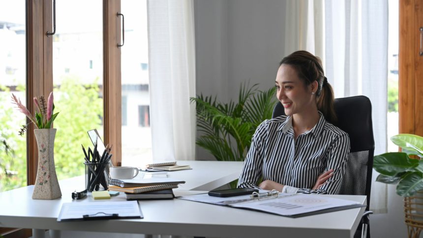 Thoughtful businesswoman team leader sitting at workplace and looking through window.