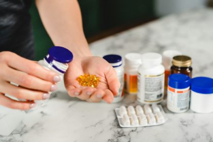 Woman is taking pills and food supplements at the kitchen table