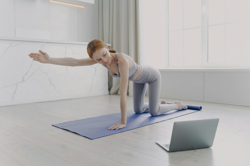 Young woman practicing yoga by video tutorial. Posture exercise. Home classes on quarantine.